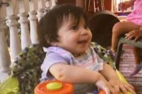 a baby sits in a toy car on a porch